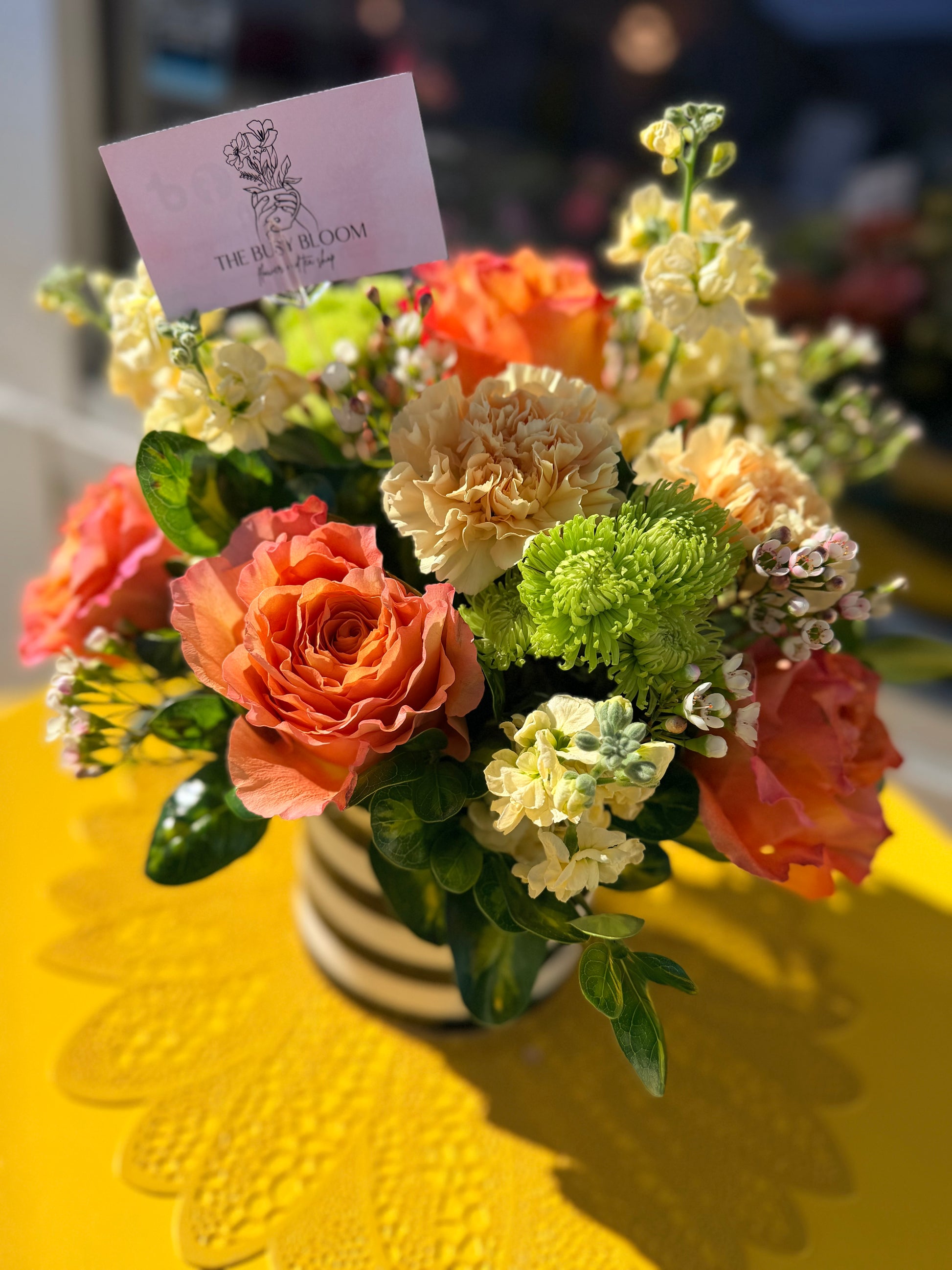 Floral arrangement with a card on a yellow tablecloth