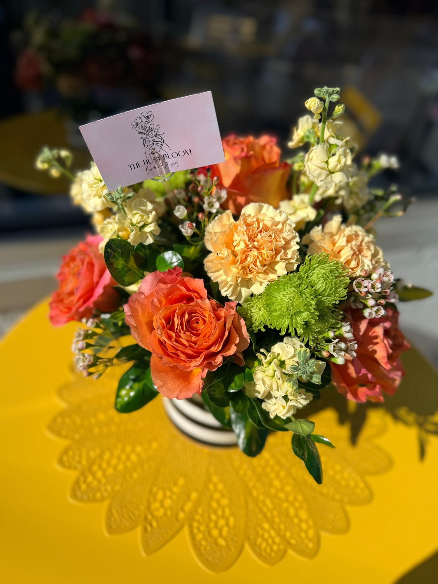 Floral arrangement with a card on a yellow tablecloth